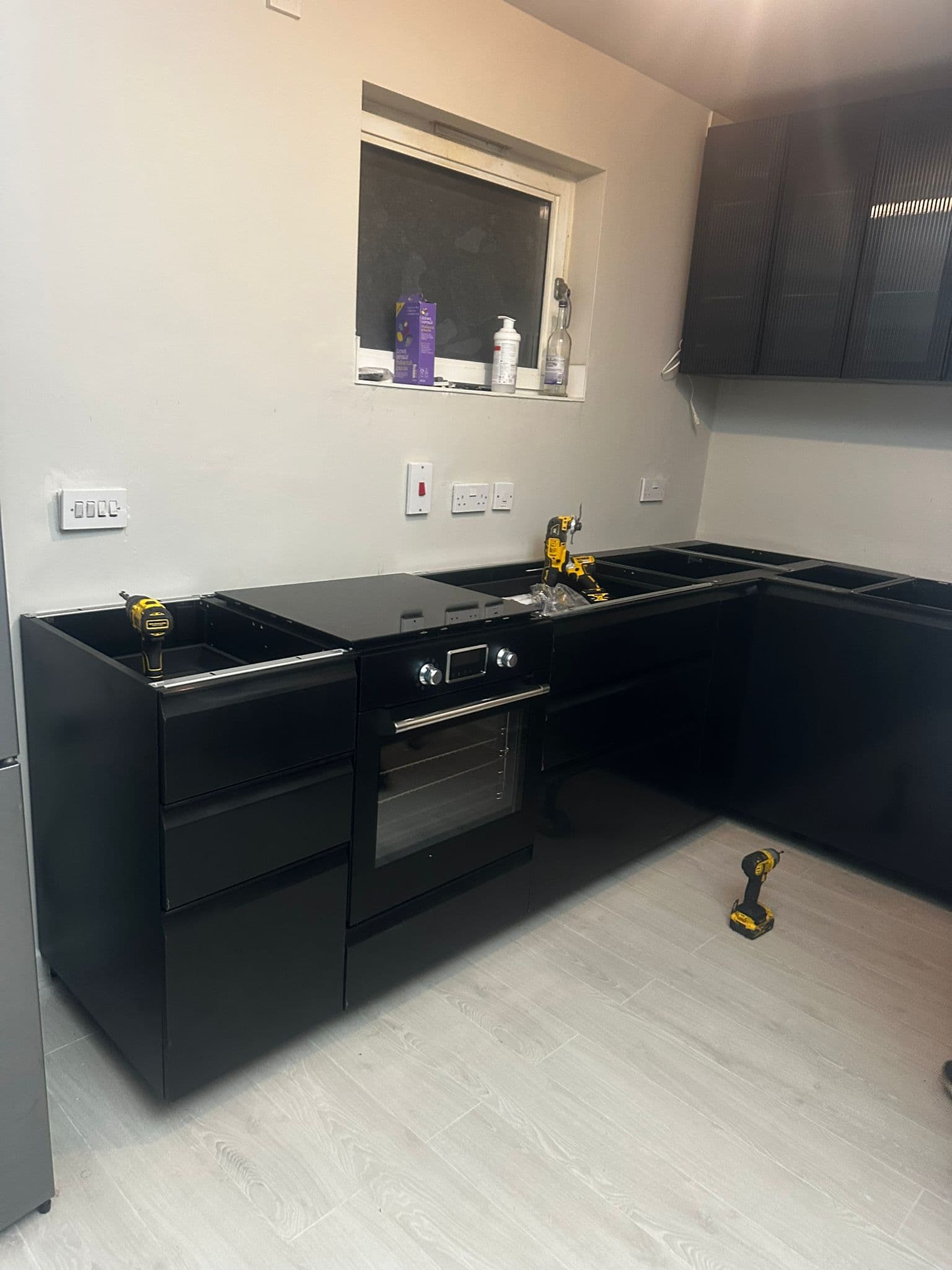 Black kitchen cabinets mid-installation showing completed work