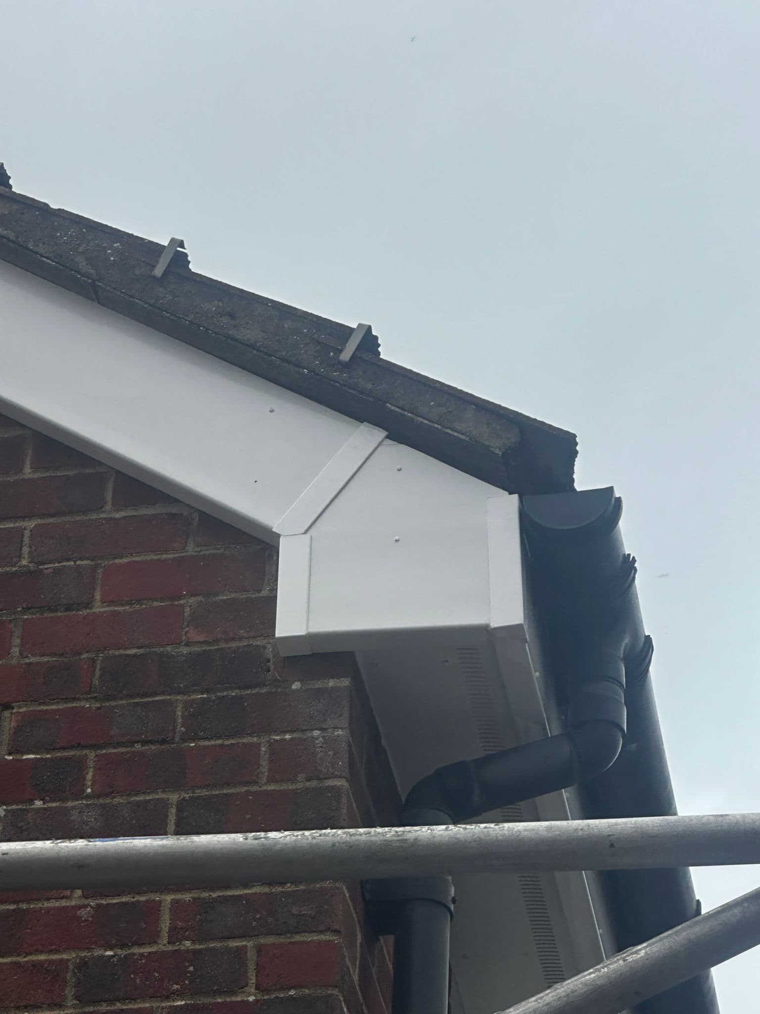 New white fascia board with black guttering and downpipe at corner detail