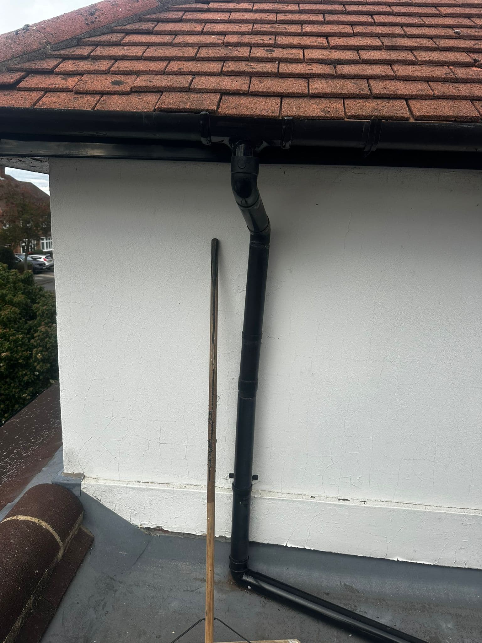 Guttering and downpipe system on roof with chimney
