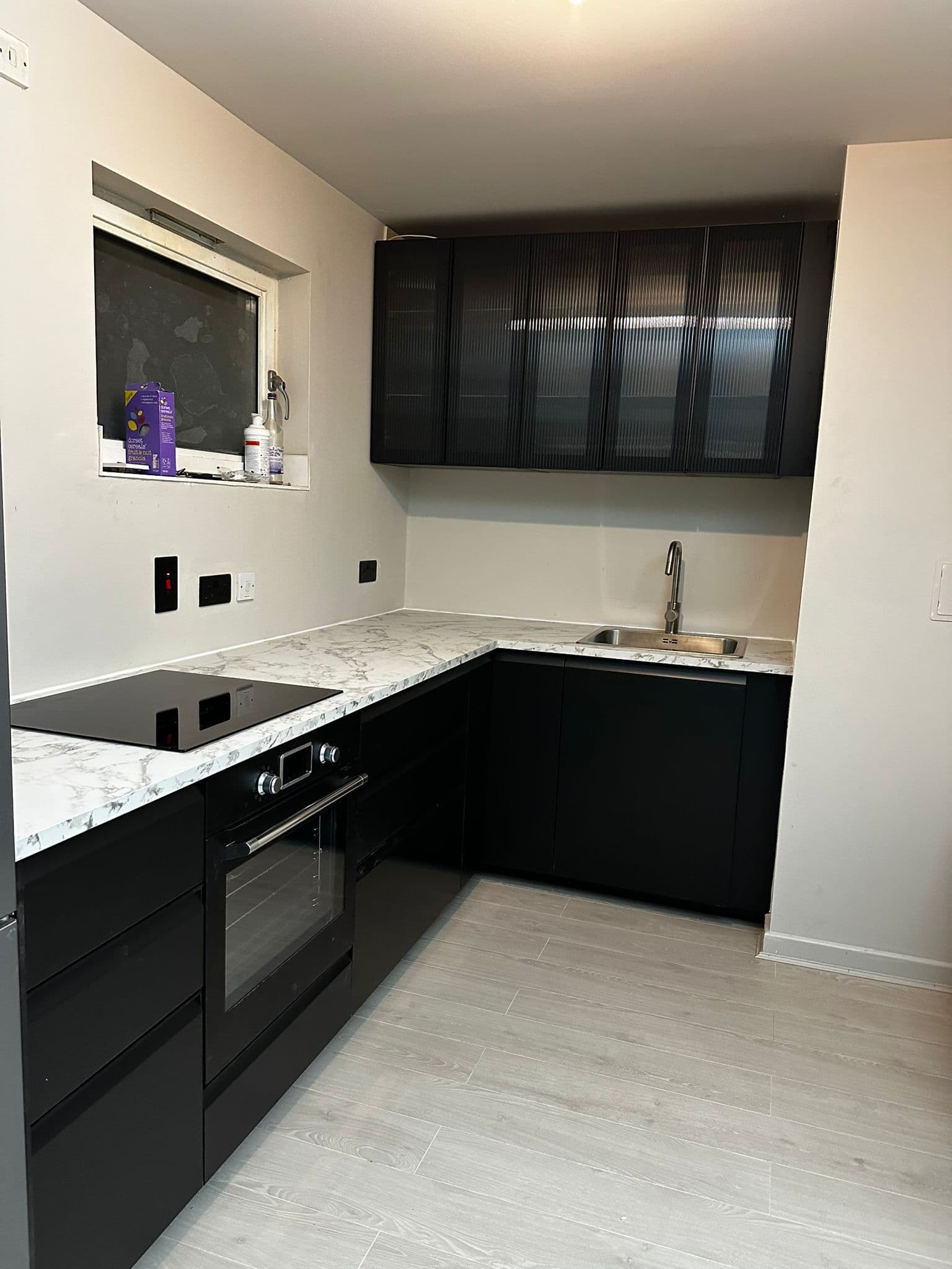 Modern black kitchen with marble-effect countertop and glass-front wall cabinets